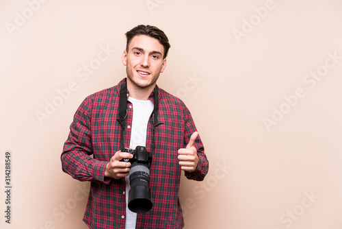 Young caucasian photographer man isolated smiling and raising thumb up
