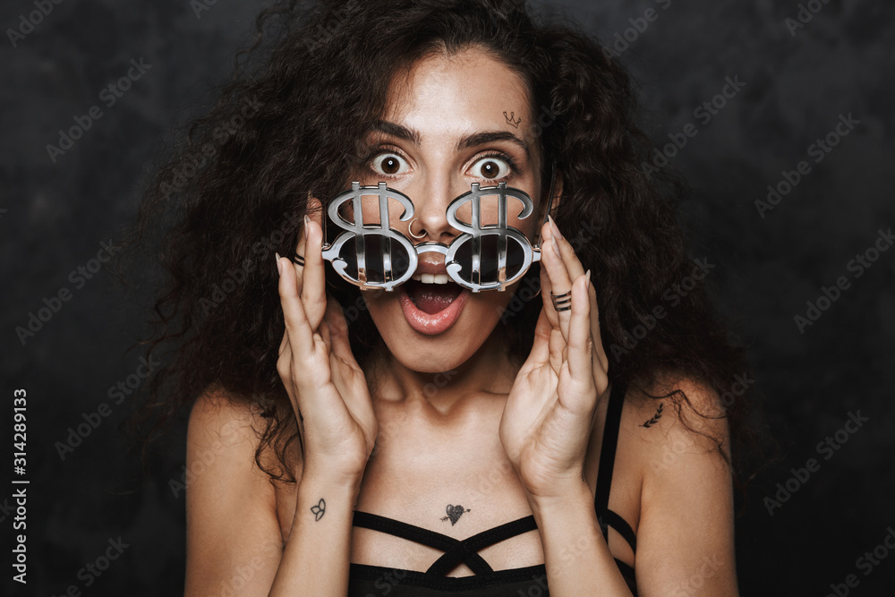 Image of nice surprised woman holding sunglasses and looking at camera