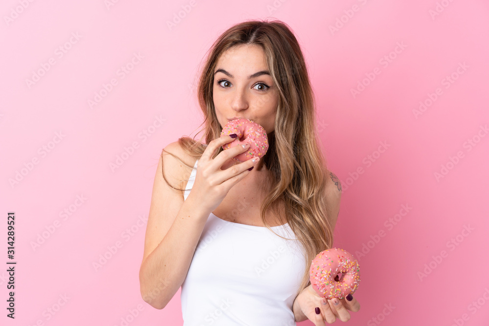 Young woman over isolated pink background holding a donut
