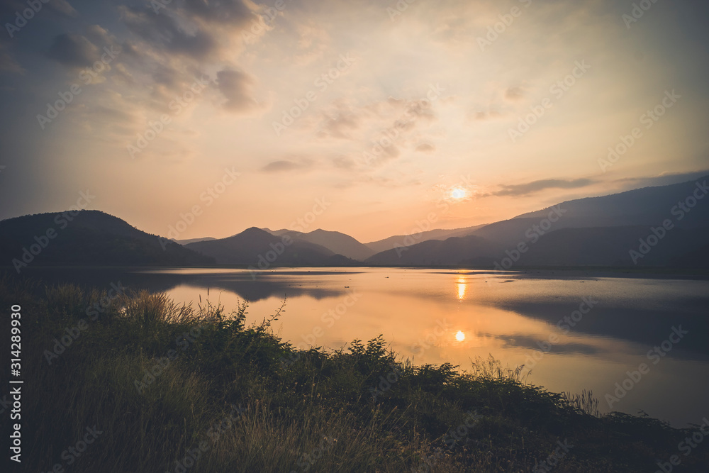 Fototapeta premium Mountain, sky and river in a quiet and cool atmosphere. Similar color scheme .View of blue mountains with reflection in lake . Landscape with blue mountains near lake in Sukhothai Thailand
