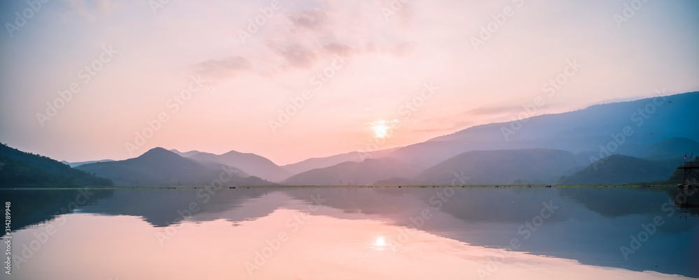 Mountain, sky and river in a quiet and cool atmosphere. Similar color scheme .View of blue mountains with reflection in lake . Landscape with blue mountains near lake in Sukhothai Thailand