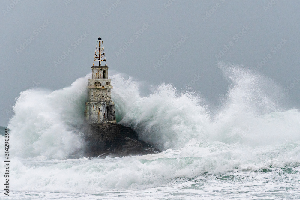 Big waves hit the lighthouse, winter sea storm. 