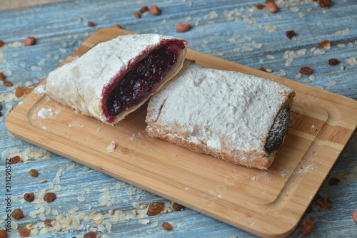 Roll with cherry and cranberry strudel with syrup on wooden table