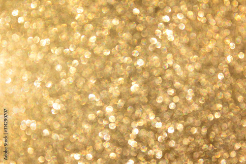 Large golden bokeh circles shine. Defocused photo of festive glitter paper.