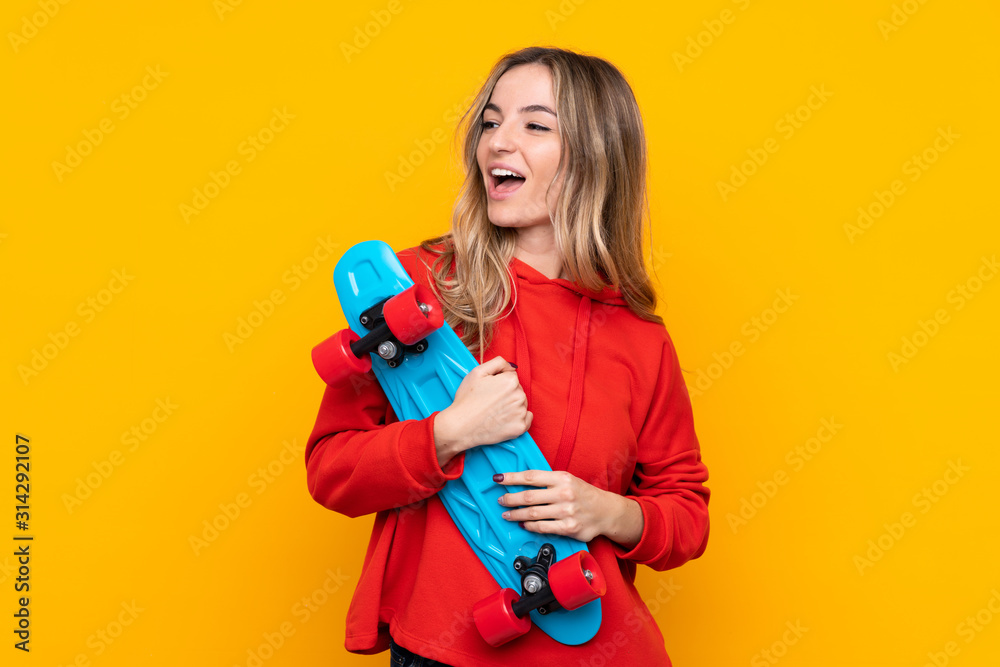 Young woman over isolated yellow background with a skate with happy expression