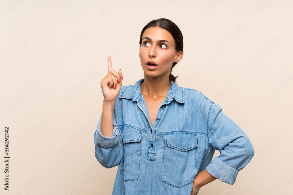 Young woman over isolated background thinking an idea pointing the finger up
