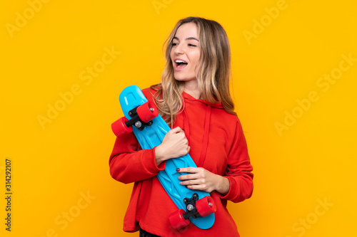 Young woman over isolated yellow background with a skate with happy expression