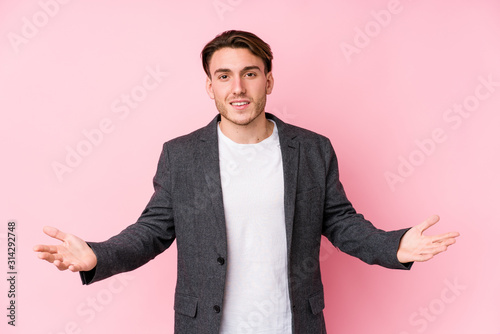Young caucasian business man posing isolated showing a welcome expression.