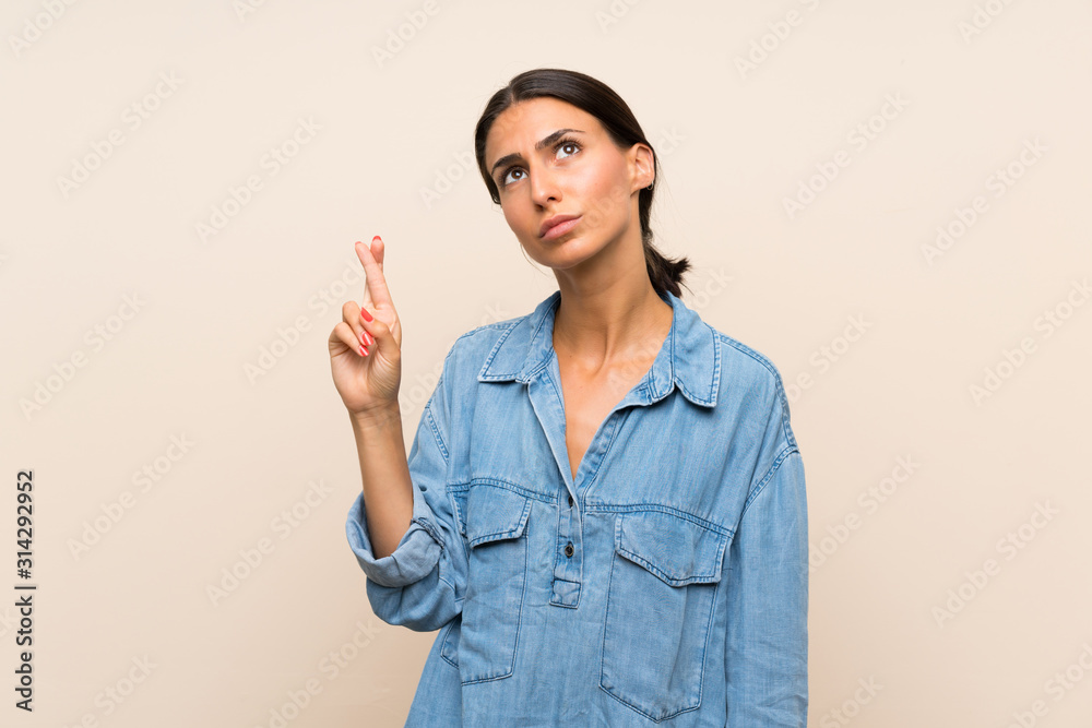 Young woman over isolated background with fingers crossing and wishing the best Young woman over isolated background with fingers crossing and wishing the best