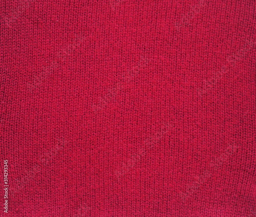 Knitted fabric texture. Red color. Garter stitch with facial loops. Knitting on the knitting needles. Knitted background.