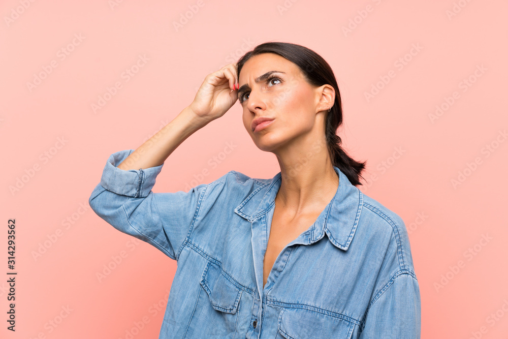 Young woman over isolated pink background having doubts and with confuse face expression Young woman over isolated pink background having doubts and with confuse face expression