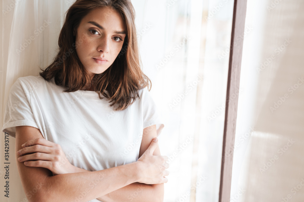Woman indoors at home posing near window. Woman indoors at home posing near window.