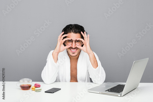 Young handsome man working after a shower showing okay sign over eyes © Asier