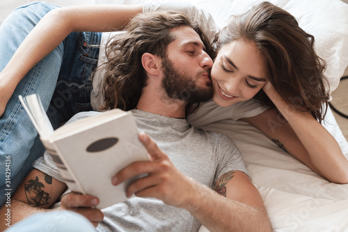 Loving couple indoors at home lies reading book together. photo