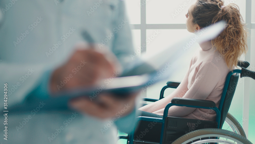 Doctor writing medical records and patient in a wheelchair - obrazy, fototapety, plakaty 