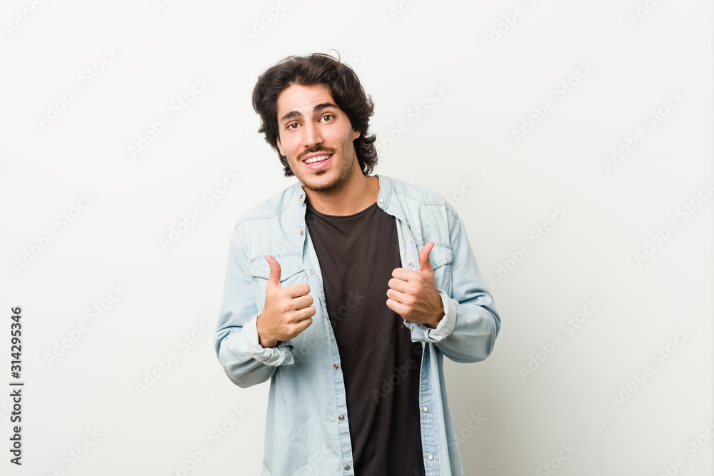 Young handsome man against a white background raising both thumbs up, smiling and confident. Young handsome man against a white background raising both thumbs up, smiling and confident.