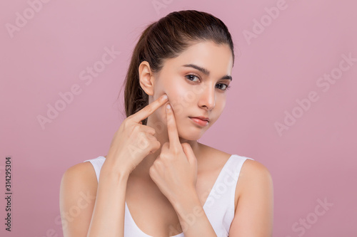 Slika na platnu Young unhappy attractive Caucasian woman worried about her red spot acne on her face trying to take it out of the skin