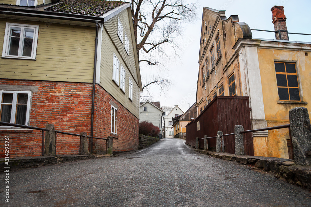 Wide angle photo of small countryside road with old houses near sides.