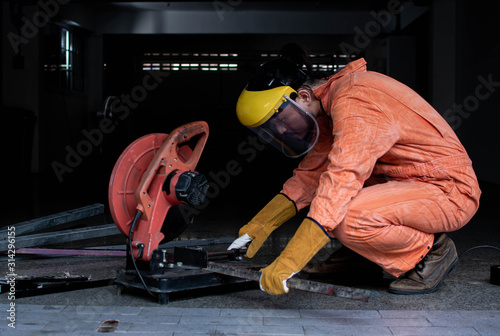 A man wearing safety mask and suit is cutting metal