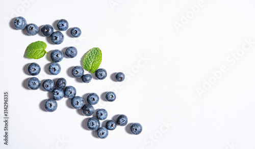 pattern of fresh  blueberries and mint leaves  is laid out on a yellow background