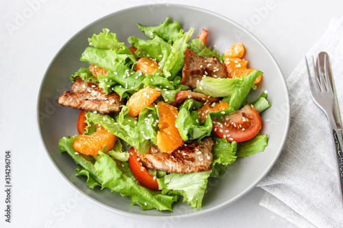 Salad with sweet tangerines and pieces of pork