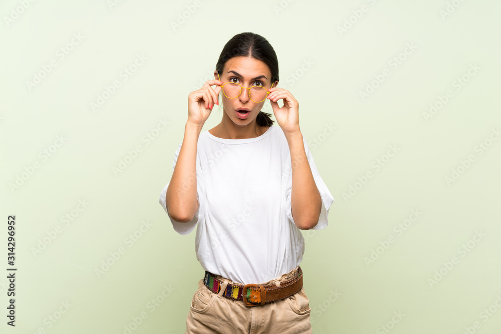 Young woman over isolated green background with glasses Young woman over isolated green background with glasses