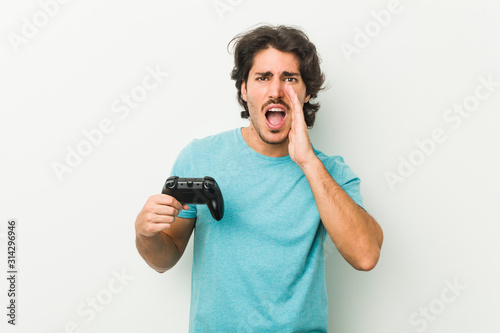 Young man holding a game controller shouting excited to front.