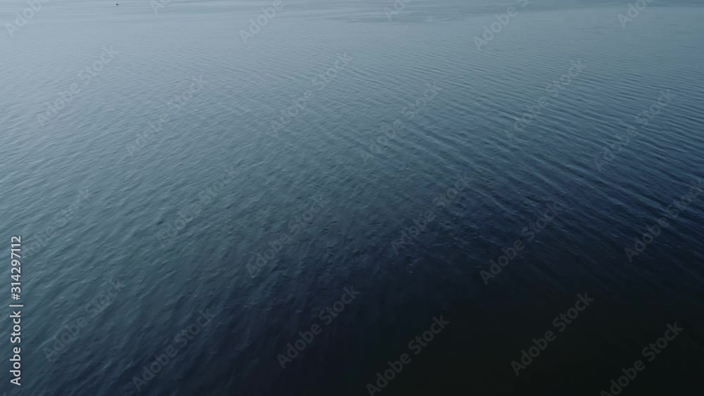 Aerial video of endless, blue, empty sea or ocean water surface at sunset. 