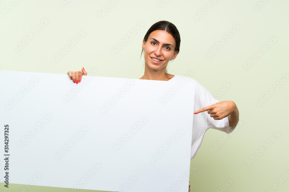 Young woman over isolated green background holding an empty white placard for insert a concept Young woman over isolated green background holding an empty white placard for insert a concept