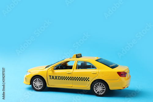 Yellow taxi car model on light blue background. Space for text