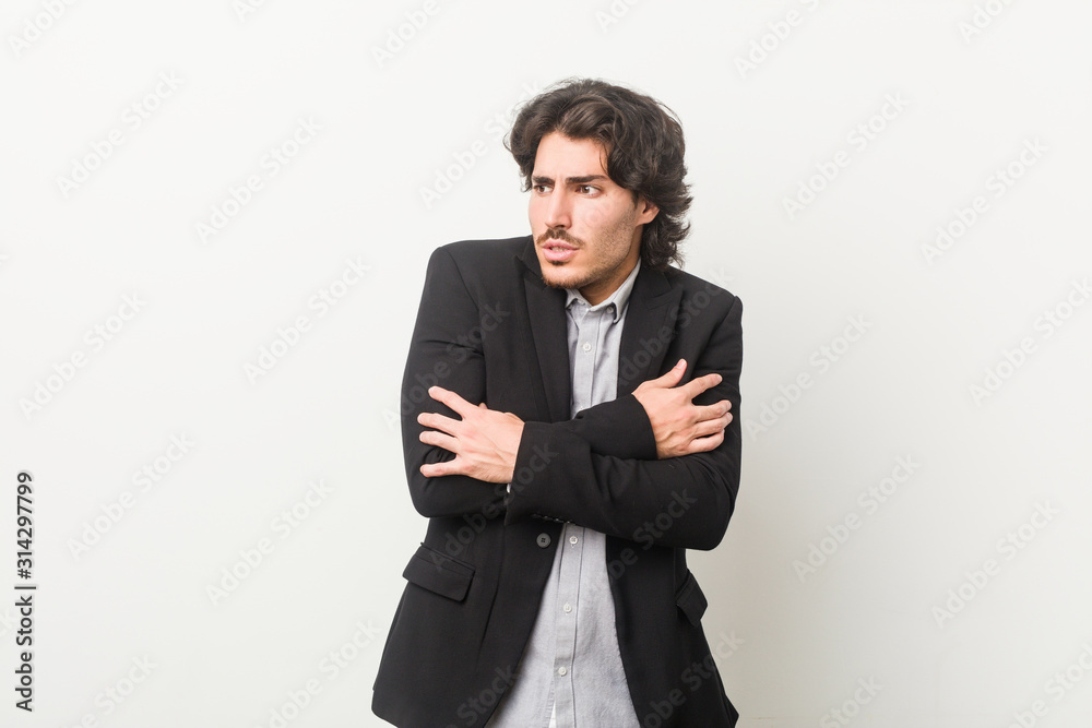 Young business man against a white background going cold due to low temperature or a sickness. Young business man against a white background going cold due to low temperature or a sickness.