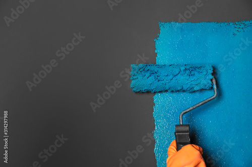 Fototapeta Naklejka Na Ścianę i Meble -  Woman painting grey wall with blue dye, closeup. Space for text