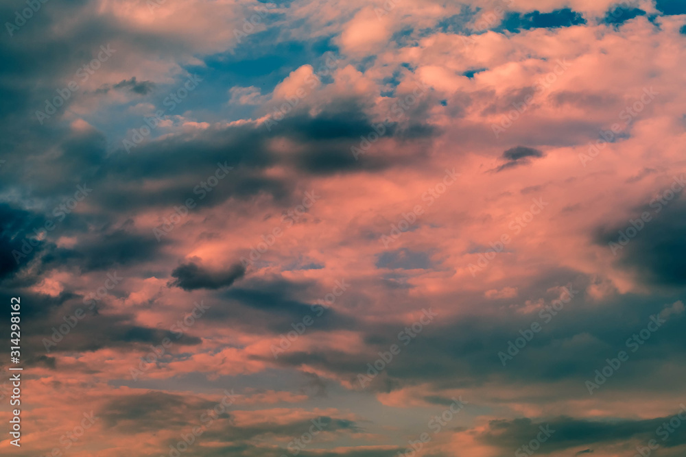 Background from Dark Thunderstorm Sky with clouds at sunset. Sun rays light clouds on top with red and orange colors.