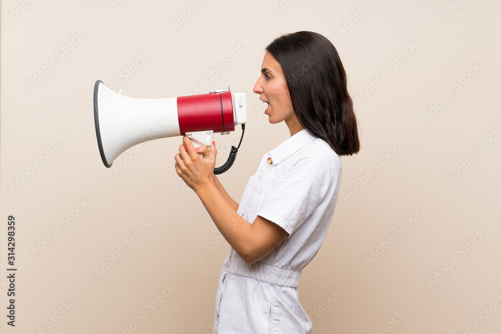 Young woman over isolated background shouting through a megaphone Young woman over isolated background shouting through a megaphone