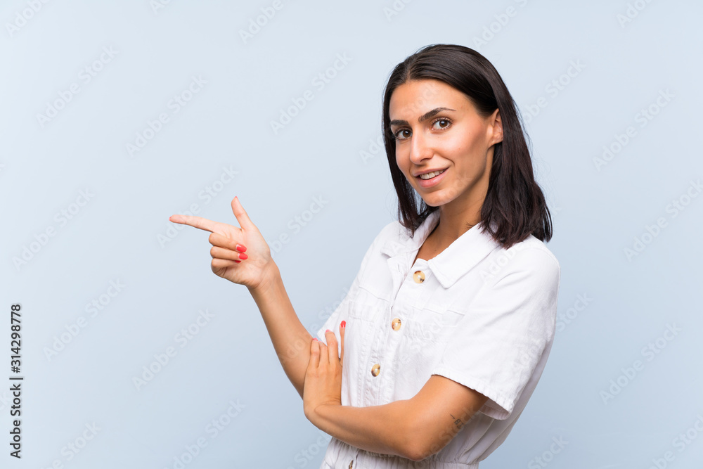 Young woman over isolated blue background pointing finger to the side Young woman over isolated blue background pointing finger to the side