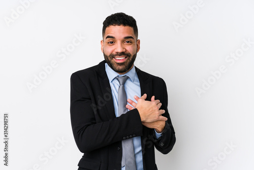 Young latin business woman against a white background isolated has friendly expression, pressing palm to chest. Love concept.