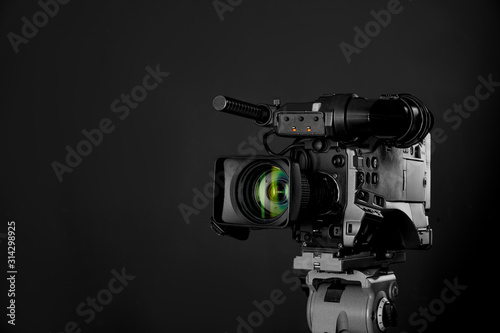 Modern professional video camera on black background. Space for text
