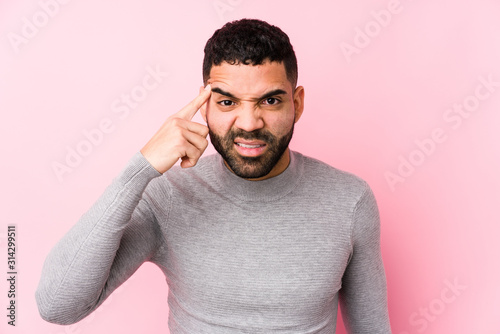 Young latin man against a pink background isolated showing a disappointment gesture with forefinger.