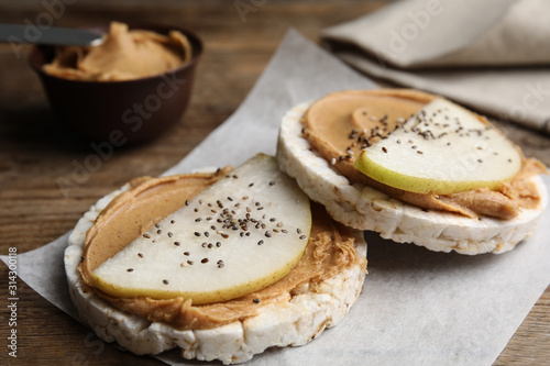 Puffed rice cakes with peanut butter and pear on wooden table