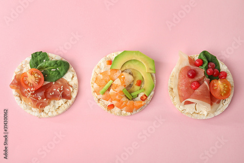Puffed rice cakes with different toppings on pink background, flat lay
