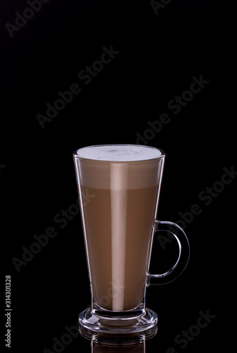 Latte coffee in glass cup with foam on black background