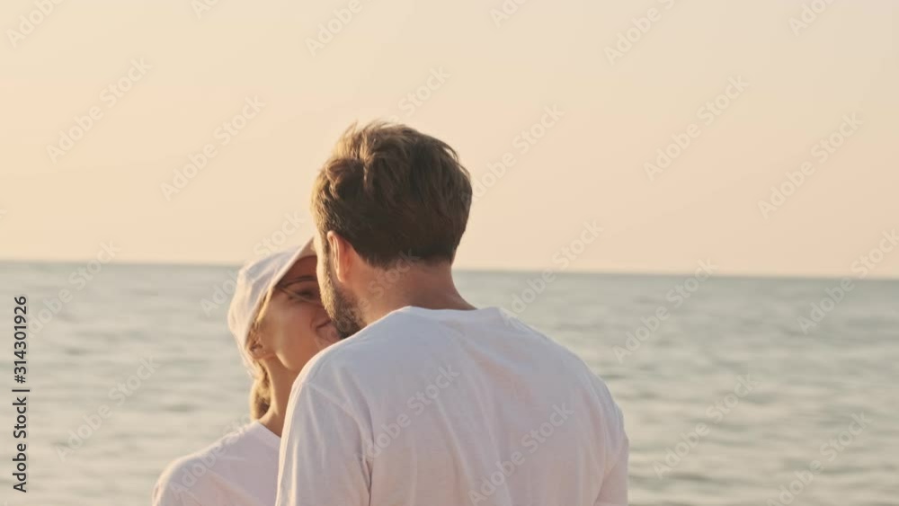 Attractive young volunteers man and woman are looking at each other and kissing after cleaning the beach from garbage early in the morning Attractive young volunteers man and woman are looking at each other and kissing after cleaning the beach from garbage early in the morning