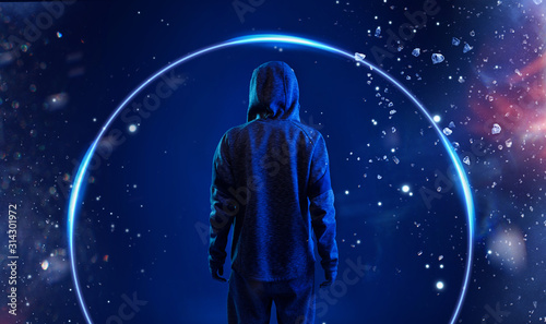 Back view of hacker in hoodie. Dangerous hooded hacker. Internet, cyber crime, cyber attack, system breaking and malware concept. Anonymous. Dark background. Blue neon light.