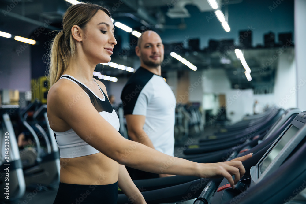 young beautiful girl and guy doing exercises in the gym, jogging on the track indoors, fitness and crossfit young beautiful girl and guy doing exercises in the gym, jogging on the track indoors, fitness and crossfit