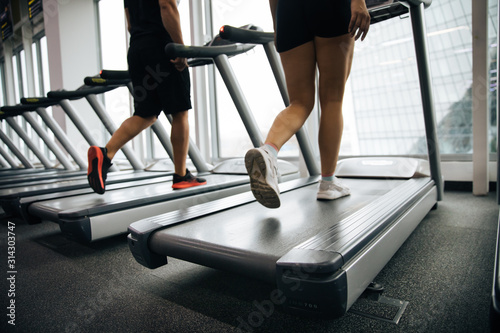 young beautiful girl and guy doing exercises in the gym, jogging on the track indoors, fitness and crossfit