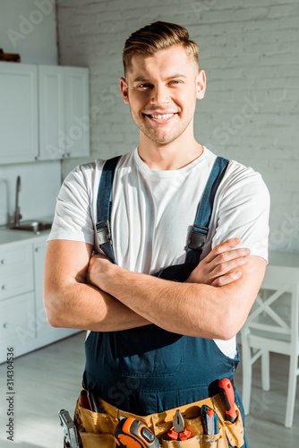 happy installer in overalls standing with crossed arms