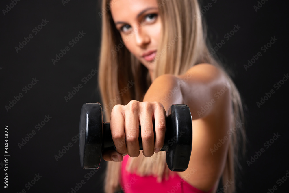 Young sport blonde woman making weightlifting over isolated black background Young sport blonde woman making weightlifting over isolated black background