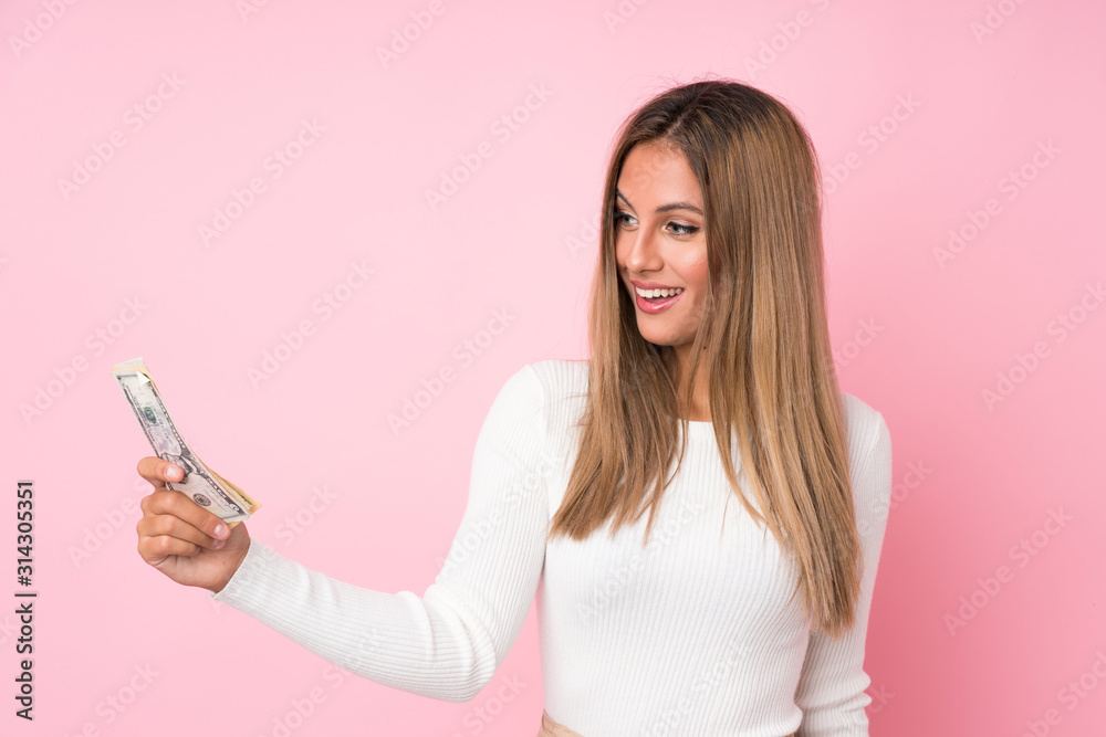 Young blonde woman over isolated pink background taking a lot of money Young blonde woman over isolated pink background taking a lot of money