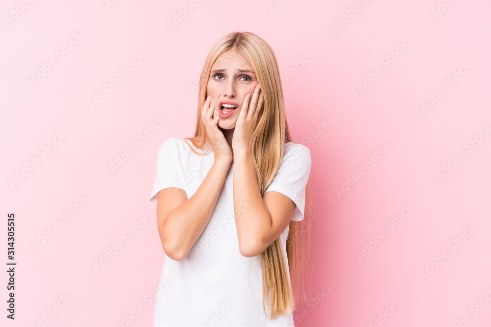 Young blonde woman on pink background whining and crying disconsolately. Young blonde woman on pink background whining and crying disconsolately.