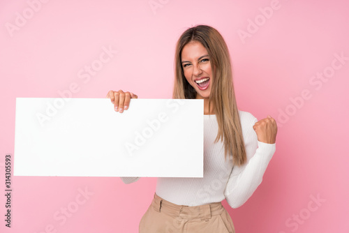 Fotografía Young blonde woman over isolated pink background holding an empty white placard